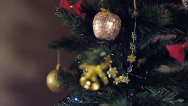 近くのフィールドの浅い深さ白人の白い女性の手はクリスマスツリーに光沢のあるおもちゃをハングアップします。浮いている焦点と新年の気分 — ストック動画