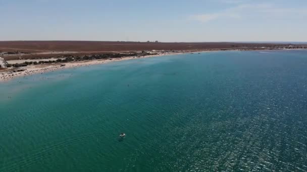 Vista aérea de uma praia turística com pessoas tendo um resto. Praia arenosa da estância balnear em um dia ensolarado. Recreação na costa oceânica — Vídeo de Stock