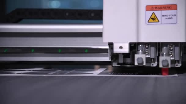 Industrieel Een close-up van een industriële plotter snijdt een sjabloon op een kartonnen verpakking voor producten. real-time ondiepe scherptediepte. Live camera — Stockvideo