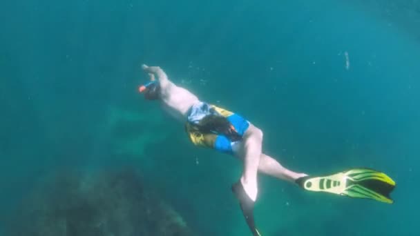 Joven hombre caucásico con una máscara de snorkel y aletas nada libre bajo el agua. Disparos con una cámara de acción — Vídeo de stock