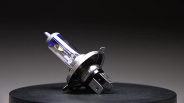 Bir araba için halojen far H4 ampulü. Ortam aydınlatma için bu yedek parça siyah bir gradyan arkaplan üzerinde döner