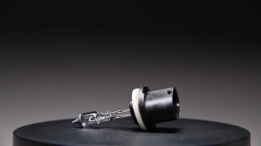 Yeni yedek parça siyah bir gradyan arka planda döner. Bir araba ampulü. h27 w1color