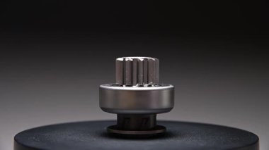Gri bir arkaplanda dönen bir parça. Başlangıç sürücüsü içten yanmalı motorun metal bir parçasıdır.