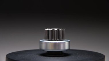 Gri bir arkaplanda dönen bir parça. Başlangıç sürücüsü içten yanmalı motorun metal bir parçasıdır.