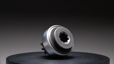 Gri bir arkaplanda dönen bir parça. Başlangıç sürücüsü içten yanmalı motorun metal bir parçasıdır.