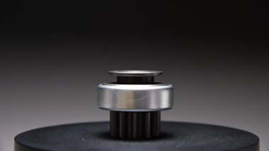 Gri bir arkaplanda dönen bir parça. Başlangıç sürücüsü içten yanmalı motorun metal bir parçasıdır.
