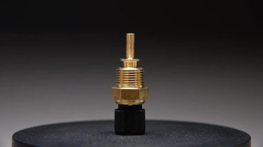 Yedek parça. Yeni motor soğutucu sıcaklık sensörü. Gradyan arkaplanda yeni bir parça döndürülüyor. Sığ alan derinliği