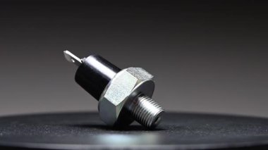 Yedek parça. Yeni motor yağı sıcaklık sensörü. Yeni parçayı eğimli bir arkaplana göre döndürüyorum. Sığ alan derinliği