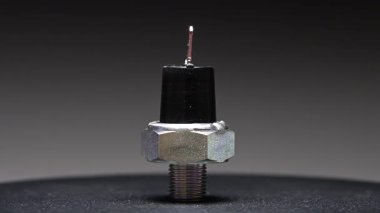 Yedek parça. Yeni motor yağı sıcaklık sensörü. Yeni parçayı eğimli bir arkaplana göre döndürüyorum. Sığ alan derinliği