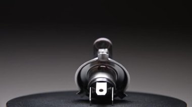 Bir araba için halojen far H4 ampulü. Ortam aydınlatma için bu yedek parça siyah bir gradyan arkaplan üzerinde döner