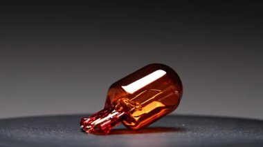 Turuncu bir araba ampulü siyah bir arka planda döner. Bu turuncu W21W park lambası otomotiv aydınlatma ekipmanları için yedek parça.