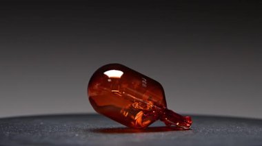 Turuncu bir araba ampulü siyah bir arka planda döner. Bu turuncu W21W park lambası otomotiv aydınlatma ekipmanları için yedek parça.