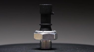 Yedek parça. Yeni motor yağı sıcaklık sensörü. Yeni parçayı eğimli bir arkaplana göre döndürüyorum. Sığ alan derinliği