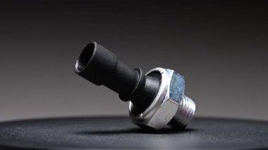 Yedek parça. Yeni motor yağı sıcaklık sensörü. Yeni parçayı eğimli bir arkaplana göre döndürüyorum. Sığ alan derinliği