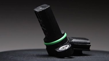 Gradyan gri arkaplanda içten yanmalı motor için yeni siyah plastik krank mili sensörü. Siyah bir platformda döner