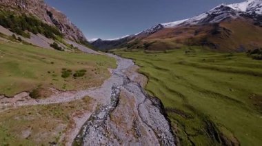 Dağlarda teknik kargo taşımacılığı yapan küçük bir yolcu helikopterinin hava görüntüsü. Quadcopter drone ile vurulmuş. Dağlarda güneşli bir gün. Hava taşımacılığı