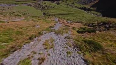 Güneşli bir günde yüksek hızda bir FPV İHA ile bir dağ uçurumunun son derece yakın uçuşu. Dağlarda yüksek dalış kuadkopteri ve İHA uçuşları