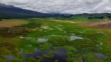 Dağların yükseklerindeki bir dağ vadisinde kıvrılan nehrin hava manzarası taşar. Gezginler doğal bir fenomen ve tatlı su kaynağı. Küresel sıcaklık.