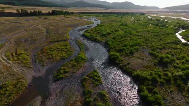 Dağların yükseklerindeki bir dağ vadisinde kıvrılan nehrin hava manzarası taşar. Gezginler doğal bir fenomen ve tatlı su kaynağı. Küresel sıcaklık.
