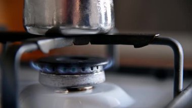 Gaz alevleri gaz sobasında parlıyor. Isı farkından dolayı buğulanmış bir kahve demliği sobanın üzerinde duruyor. Evde kahve yapıyorum. Yakın plan.