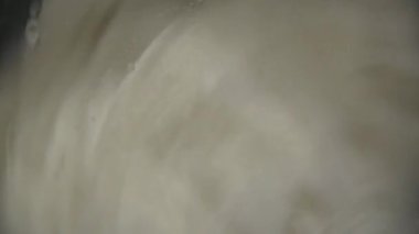 Otomatik bir çamaşır makinesi kirli beyaz giysileri yıkar. Çamaşır makinesinde çamaşır yıkamak. Bir çamaşır makinesinin dönen davulunun yakın çekim videosu