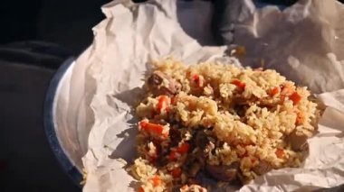 Yeni pişirilmiş sıcak pilav parşömen kaplı bir tepsiye konur. Lezzetli bir Kazak etnik yemeği. Yakın plan.