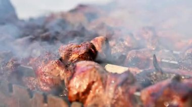 Yakın plan ateşte kızartılmış sulu et, dumanlı et. Şiş kebap sıcak kömürlerin üzerinde pişirilir. Izgarada et pişirme kavramı