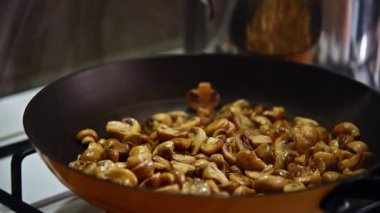 Mutfaktaki gaz sobasında tavada kızartılan küçük altın mantarların yavaş çekimleri.