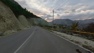 Dolambaçlı bir asfalt dağ yolunda araba sürüyorum. Dağlık arazide asfalt bir yol. Birinci şahıs görüntüsü, hareket bulanıklığı olmayan bir aksiyon kamerasıyla çekildi