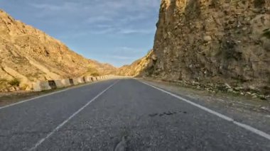Dolambaçlı bir asfalt dağ yolunda araba sürüyorum. Dağlık arazide asfalt bir yol. Birinci şahıs görüntüsü, hareket bulanıklığı olmayan bir aksiyon kamerasıyla çekildi