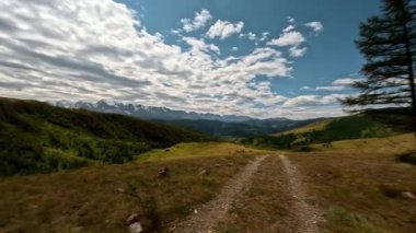 Bir arabanın ön camından birinci şahıs görüntüsü. Orman ve dağlarla çevrili toprak bir yol boyunca araba sürüyorum. Aksiyon kamerasıyla çekilmiş.