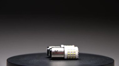 Farklı tabanlara sahip LED ampuller gri bir gradyan arkaplan üzerinde döner. Arabanın iç ve dış aydınlatma için yeni parçalar