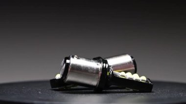 Farklı tabanlara sahip LED ampuller gri bir gradyan arkaplan üzerinde döner. Arabanın iç ve dış aydınlatma için yeni parçalar