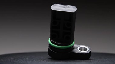 Bir araba için yeni bir krank mili sensörü. Yeni parça gri bir gradyan arkaplan üzerinde döner