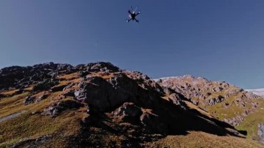 Güneşli bir günde dağlarda uçan bir İHA 'nın havadan görünüşü. Kendi kendine kurulmuş bir İHA 'yı takip ediyor ve takip ediyor.