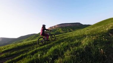 Genç bir erkek bisikletçi, dağlarda yavaş çekimde bisikletiyle geziyor. Fpv insansız hava aracının epik kaya dağları görüntüsü.