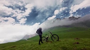 Genç adam dağlarda bisikletine biniyor. FPV İHA 'dan hava görüntüsü. mtb yokuş aşağı bisiklet sürücüsünün başlangıcı.