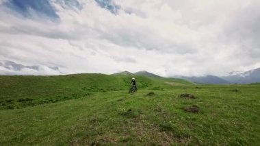 Fpv insansız hava aracı profesyonel spor dağ bisikleti Valley Mountain Panorama 'daki yeşil çimenleri takip ediyor. FPV insansız hava aracı hızlı sürme yarışı serbest dinamik yaşam tarzı hobisi.