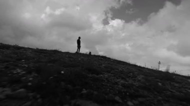 Dağın tepesinde dinlen. Spor anlayışı ve aktif yaşam tarzı. Sporcu tepede dinlenirken dağ manzarasının keyfini çıkarıyor, tek renkli..