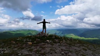 AERİAL Şut - Zinde genç bir adam bir tepenin zirvesine koşar ve kollarını zaferle kaldırarak vadinin güzel manzarasına bakar. Erkek bir sporcu zorlu bir çalışmanın sonunu kutluyor..