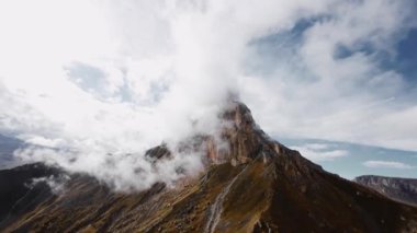 Hava sinemasının hava manzarası alçak bulutların arasında ve yanında destansı bir dağ arazisindeki kaya oluşumlarında dinleniyor..