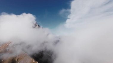 Hava manzaralı sinemalar bulutların arasında süzülür. Alçak bulutlar, destansı dağlık arazide kaya oluşumlarında yatar. Fpv İHA görüntüsü