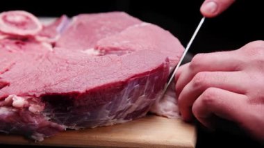 Bir kasap, karanlık bir odada büyük bir bıçakla fasyayı biftekten ayırır..