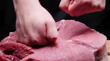 Tanımlanamayan adamların ellerini ovuşturup pişirmeden önce büyük biftekli çiğ eti yoğururken yakın çekim..