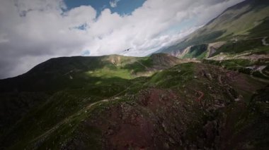 FPV, yırtıcı bir kartalın ya da vahşi bir akbabanın yanında uçuyor. Dağların tepesinde, hasta bir yırtıcı kuşu takip eden havadan bir görüntü. Yavaş çekim.