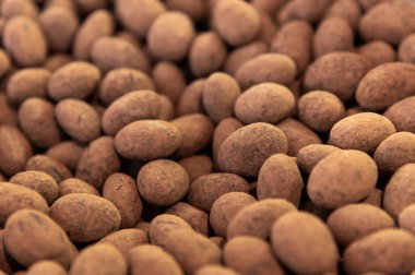 Arkaplan olarak kakao tozlu çikolata kaplı fındıklar. Koyu çikolata kabuğundaki fındık bolluğu..