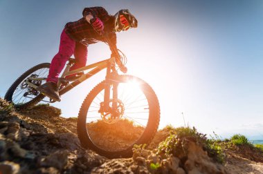 Bir dağ bisikletinin tepesinde tepetaklak giden bir sürücüden gelen güneş ışığı. Dağlarda bir yamaçtan aşağı at sürüyorum.
