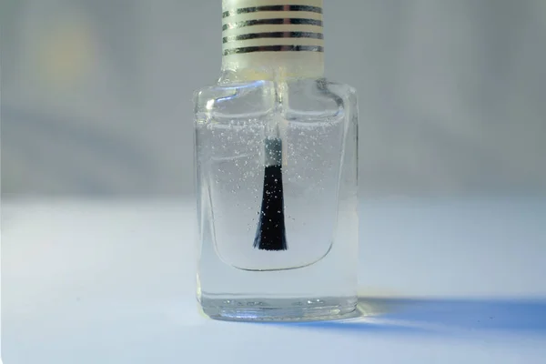 Bottle of clear nail polish with brush.