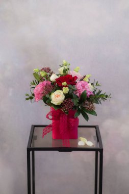 Işık arkaplanındaki masada vazodaki çiçekler 