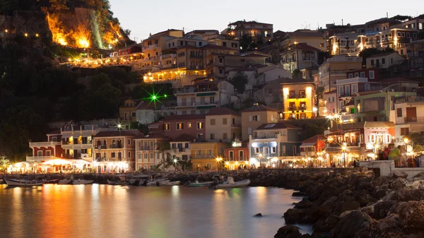 Noite em Parga, Grécia. Uma vista na fortaleza, casas e barcos perto da costa rochosa . — Fotografia de Stock